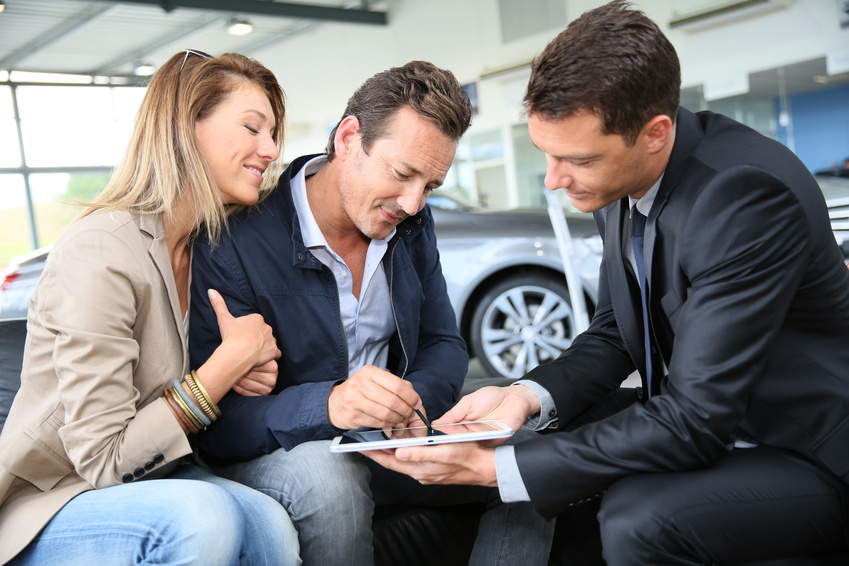 Couple signing car purchase order on digital tablet