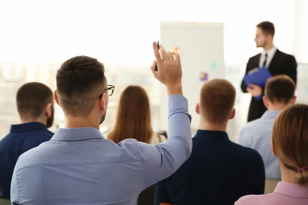 Homme levant la main pour poser des questions lors de la formation professionnelle