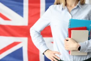 formation en langue anglaise femme tenant des livres devant le drapeau britannique